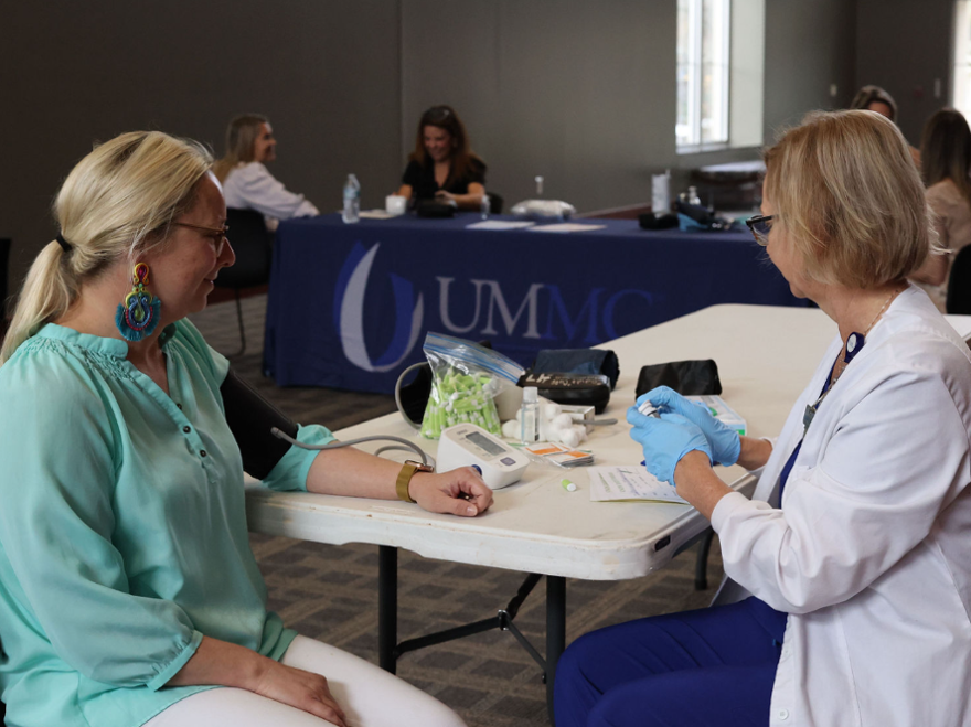 family nurse practitioner gets ready to perform a blood glucose check during a health screening